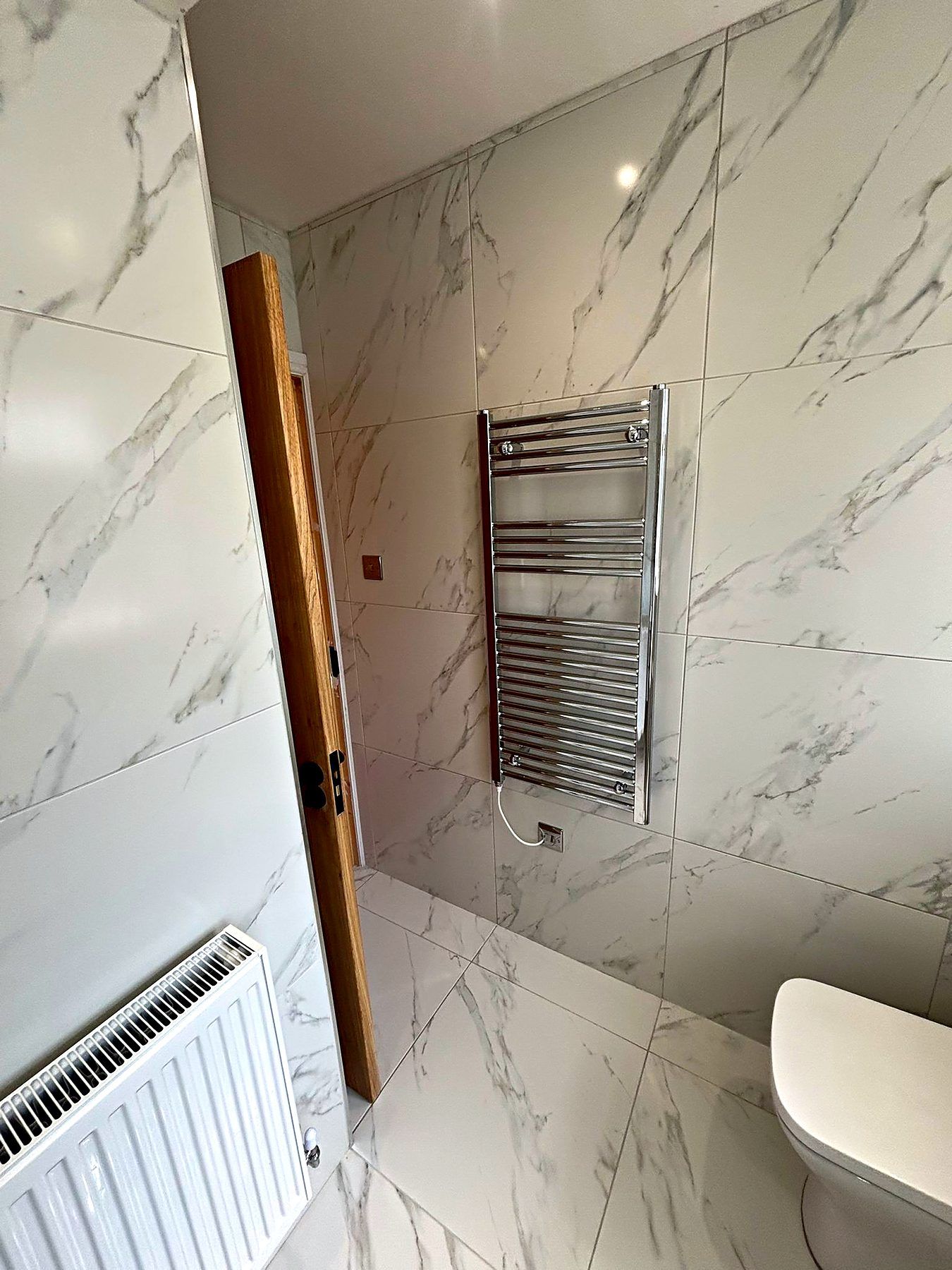 Marble-effect tiled en-suite with a chrome heated towel rail