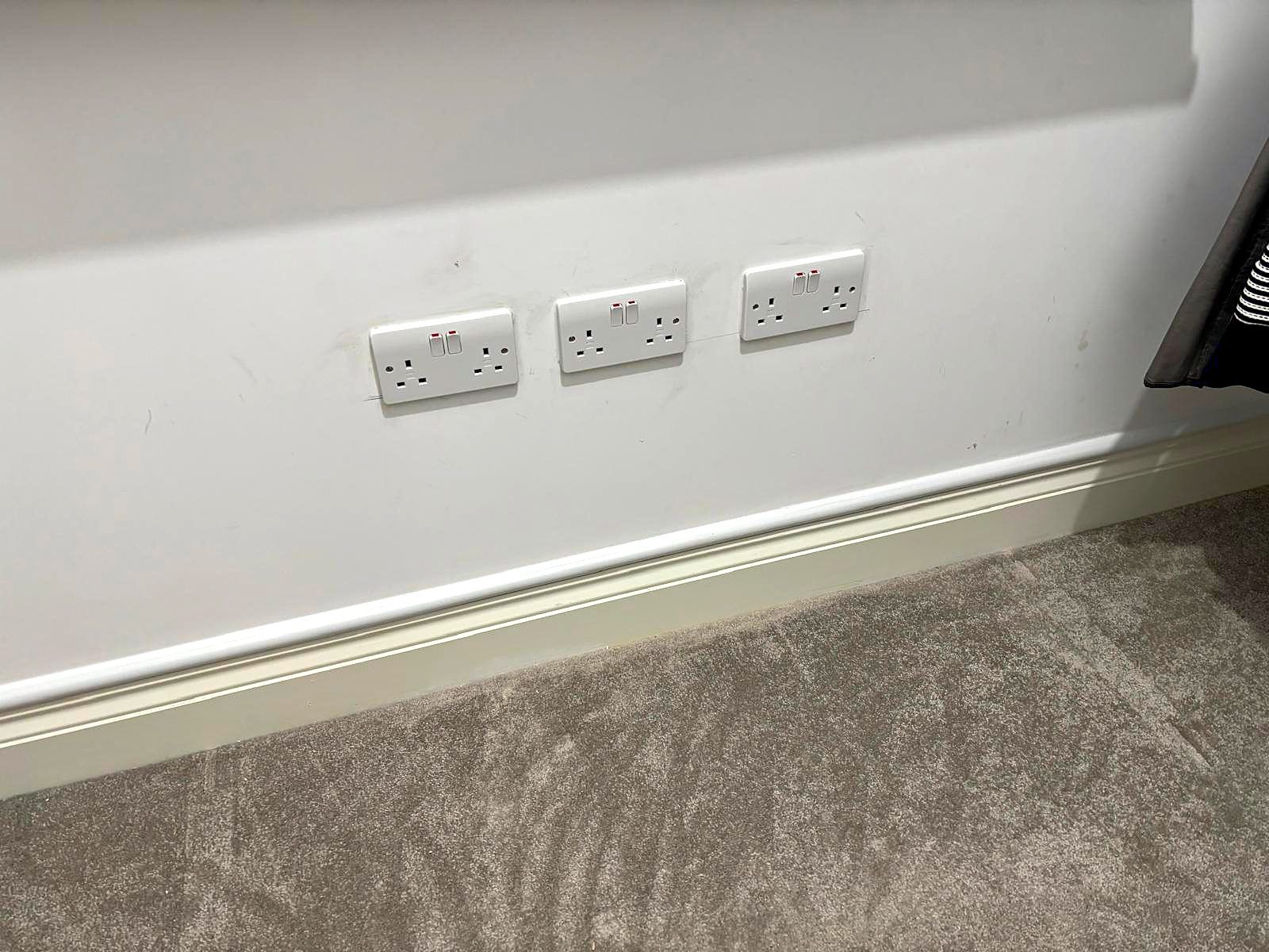 Three new white double sockets set evenly above a skirting board