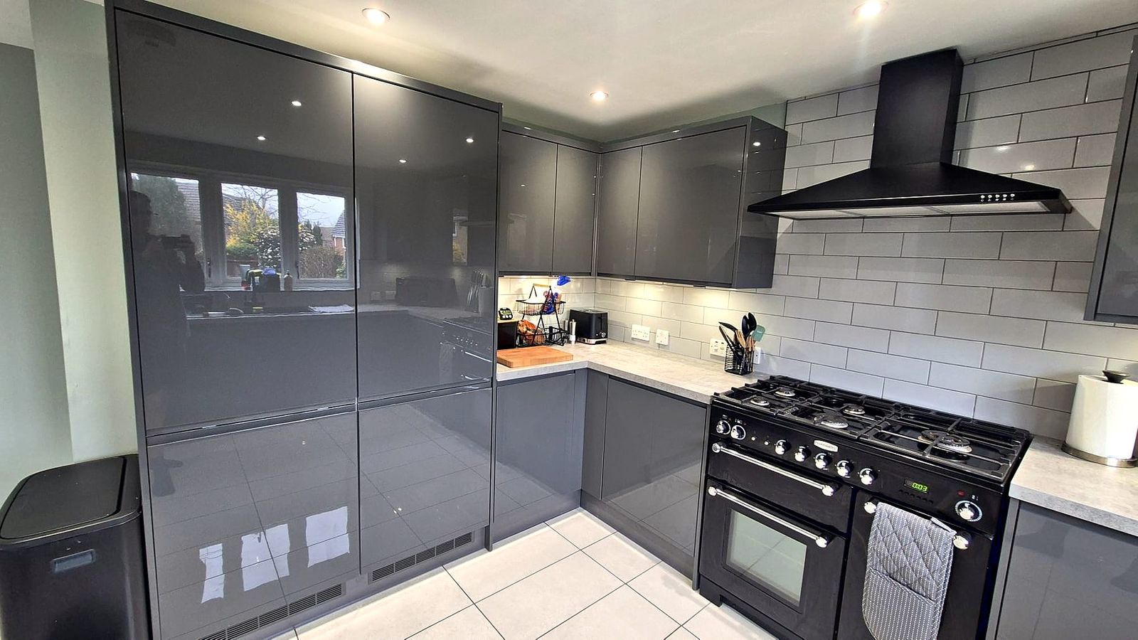 Graphite gloss kitchen with full-height larder units and a range cooker