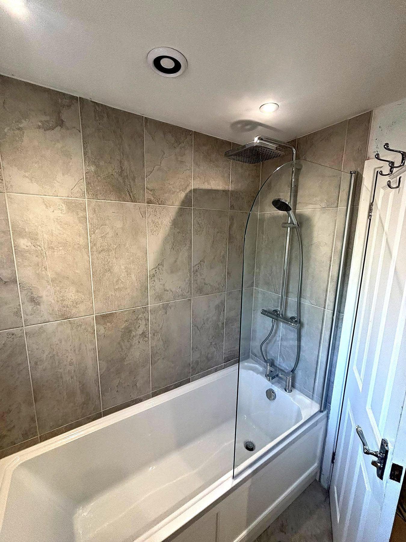 Shower over bath with rainfall head, glass screen and large grey tiles