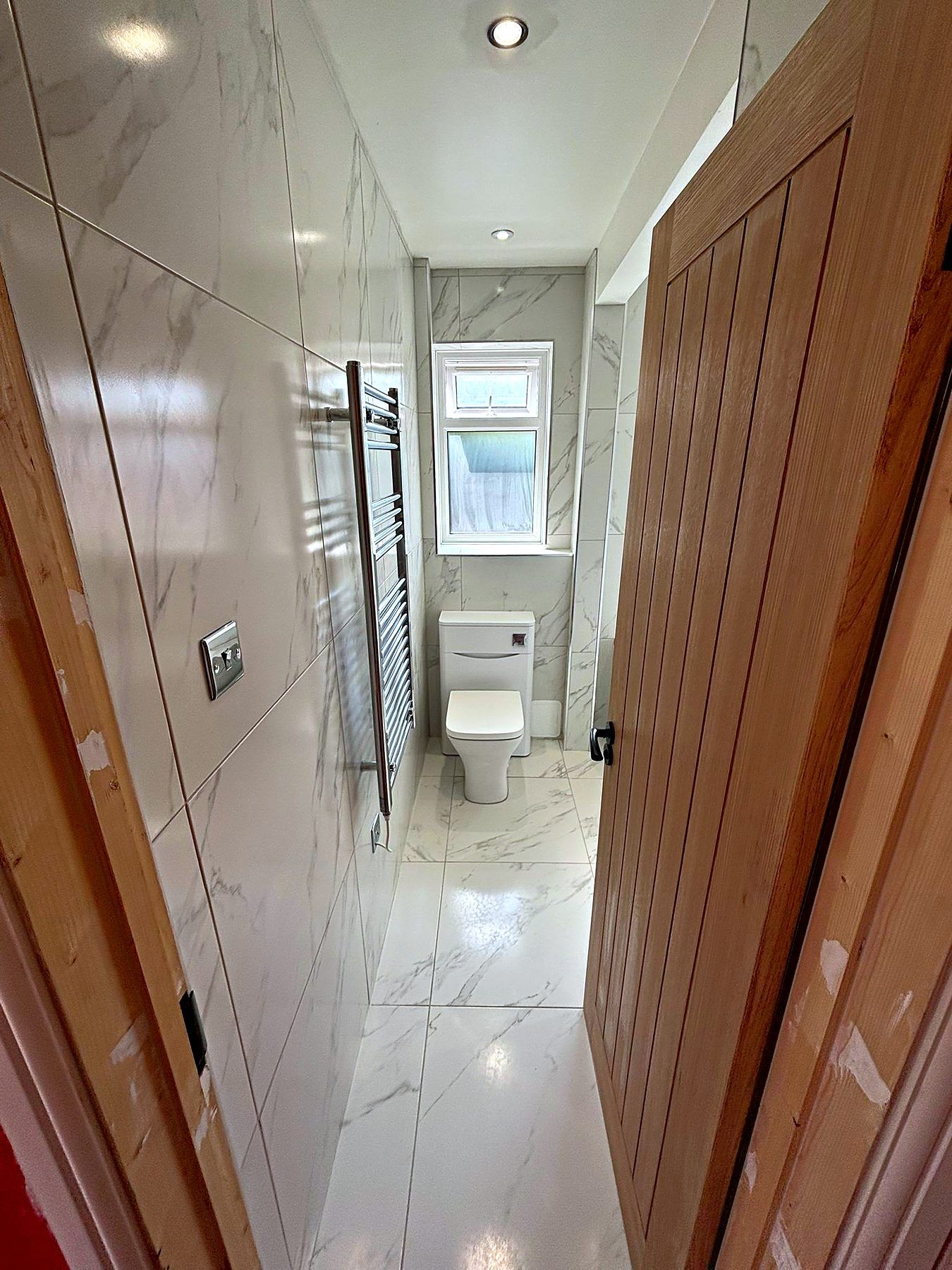 Marble-effect tiled en-suite seen through a solid oak cottage door