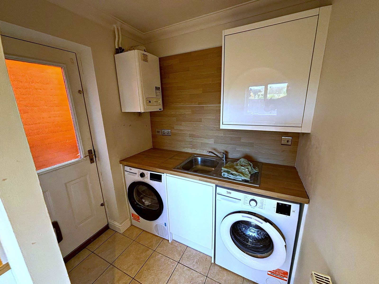 Utility room with white gloss wall unit, oak worktop, sink and space for two appliances