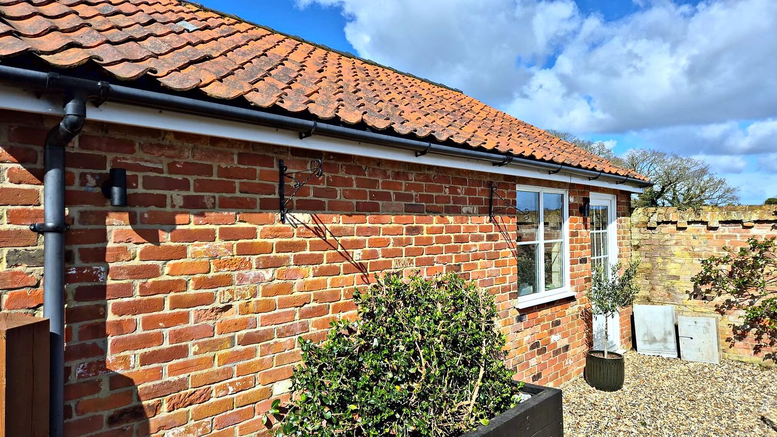 Red brick bungalow with black exterior wall lights fitted along the elevation