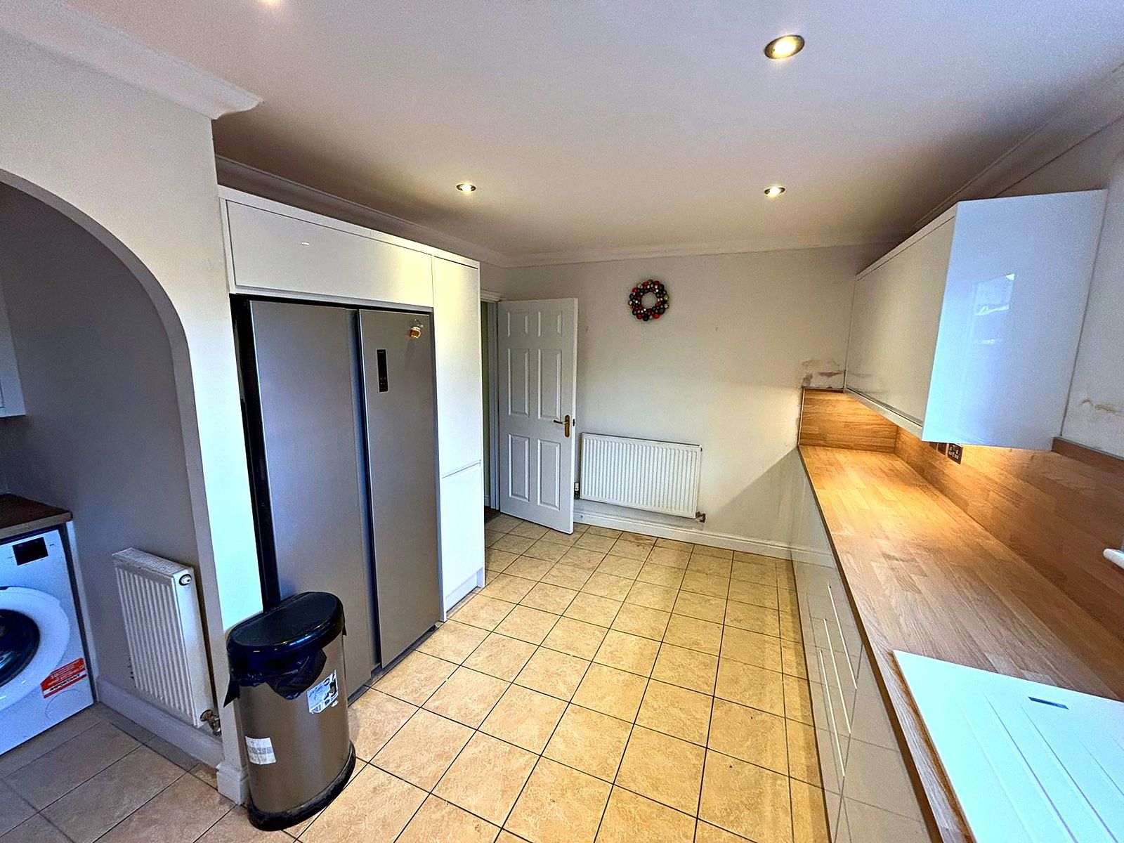 White gloss kitchen with American fridge freezer, oak worktop run and tiled floor