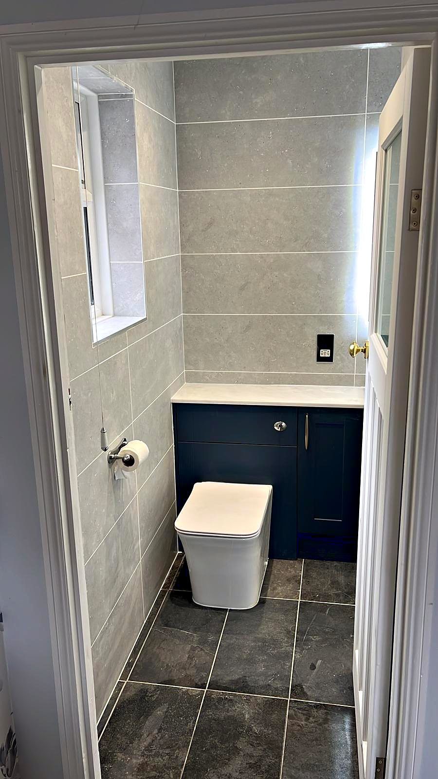 Cloakroom WC with navy vanity unit, grey tiling and slate-effect floor