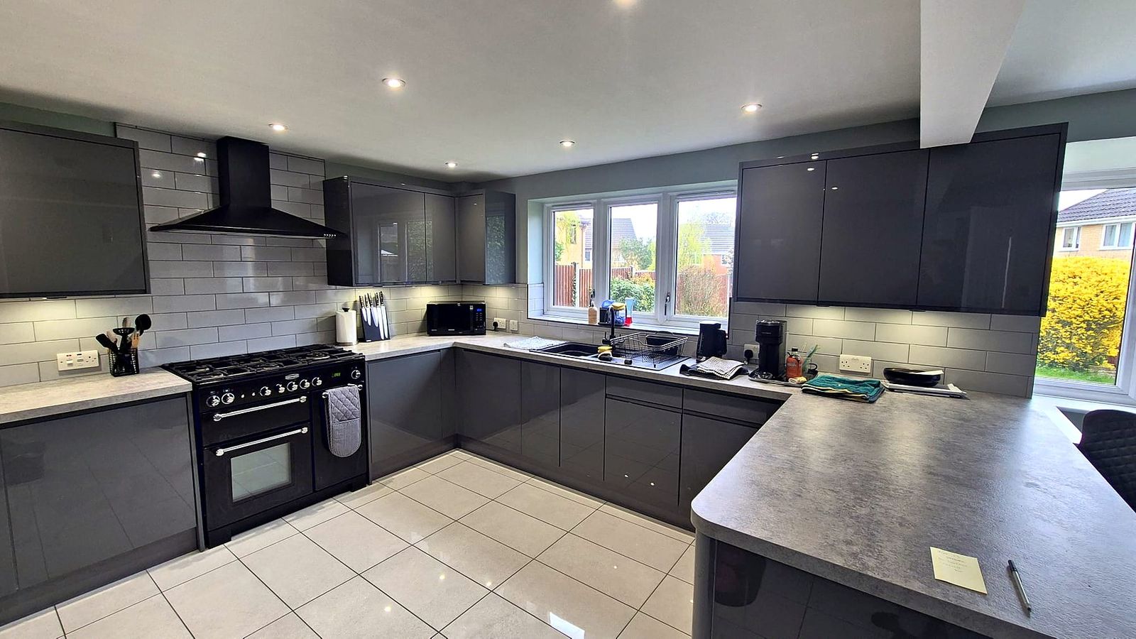 Graphite gloss kitchen with range cooker, chimney hood, metro tiling and peninsula