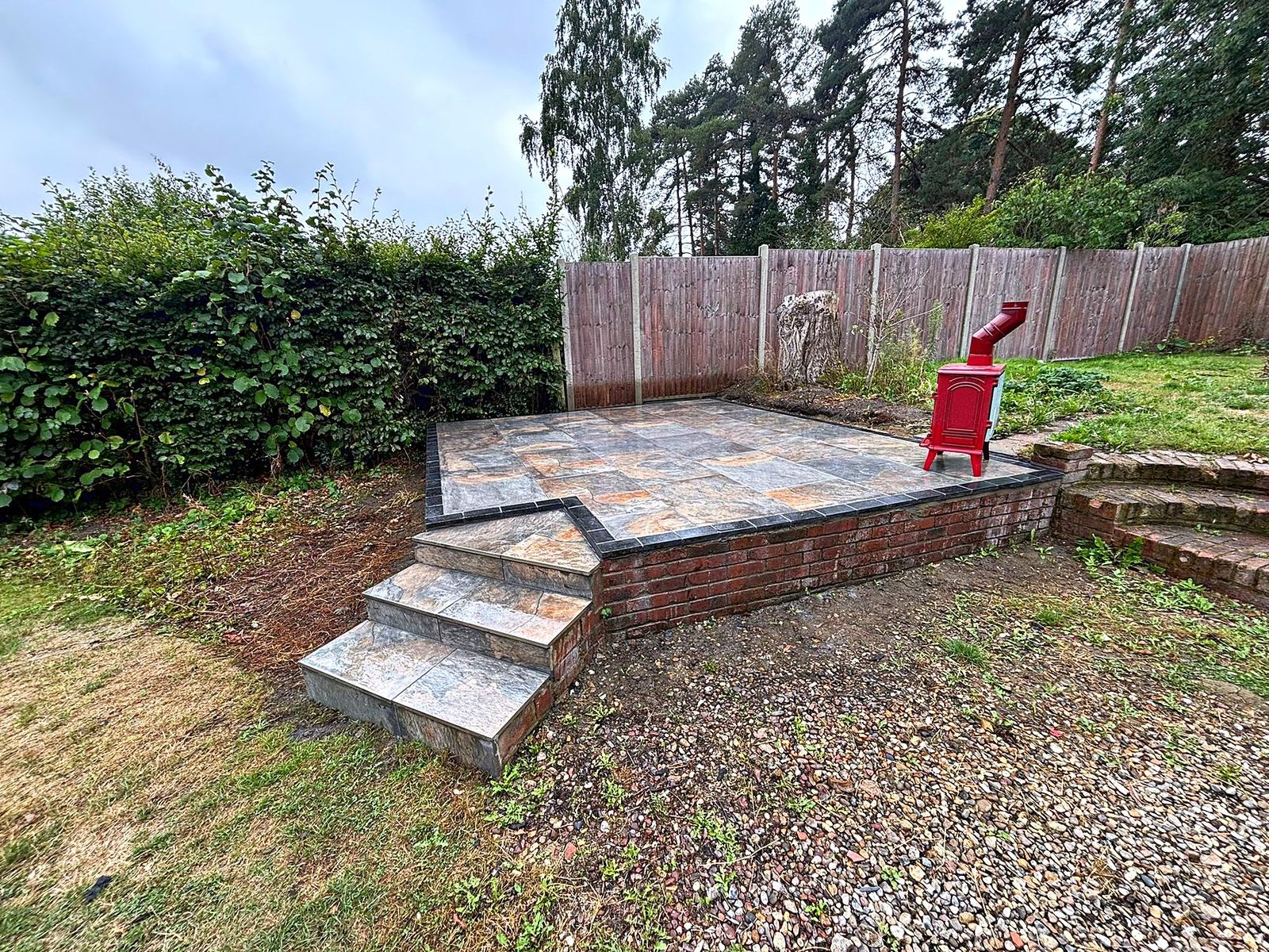 Raised porcelain-tiled patio on a brick plinth with matching tiled steps