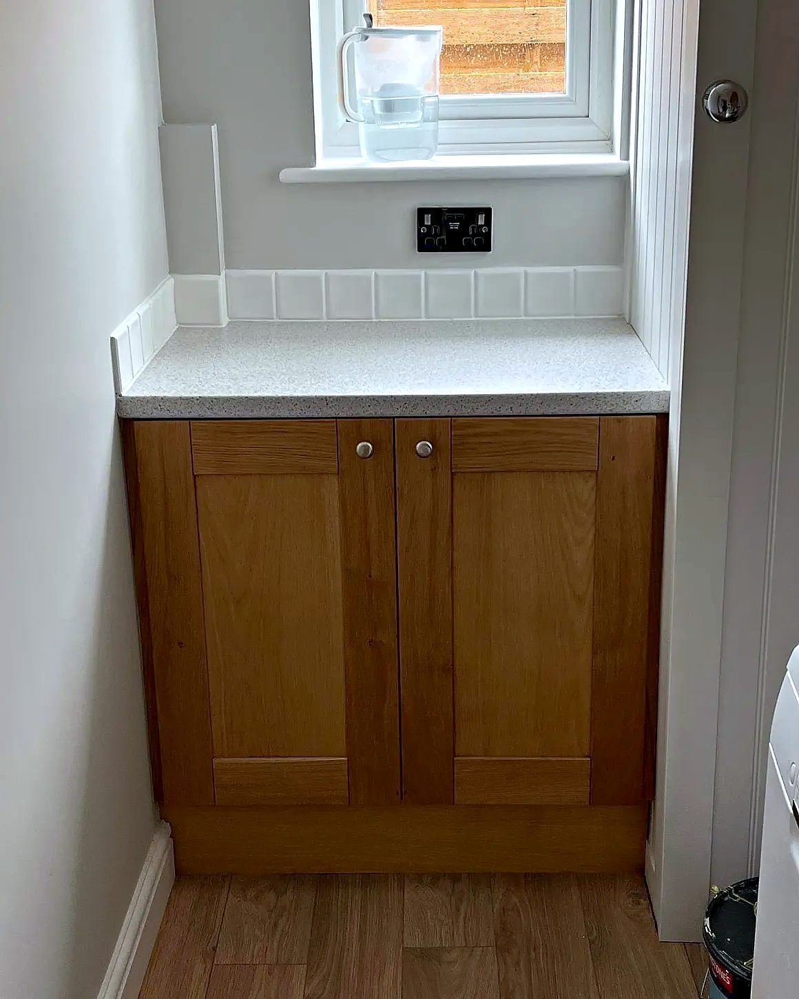 Oak shaker cupboard with sparkle worktop and tiled upstand fitted beneath a window