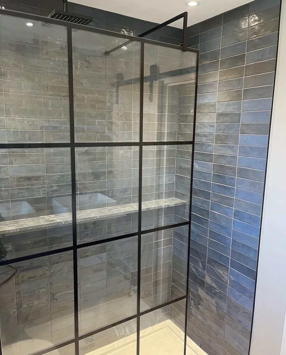 Walk-in shower detail with black framed glass screen and blue-grey metro tiling