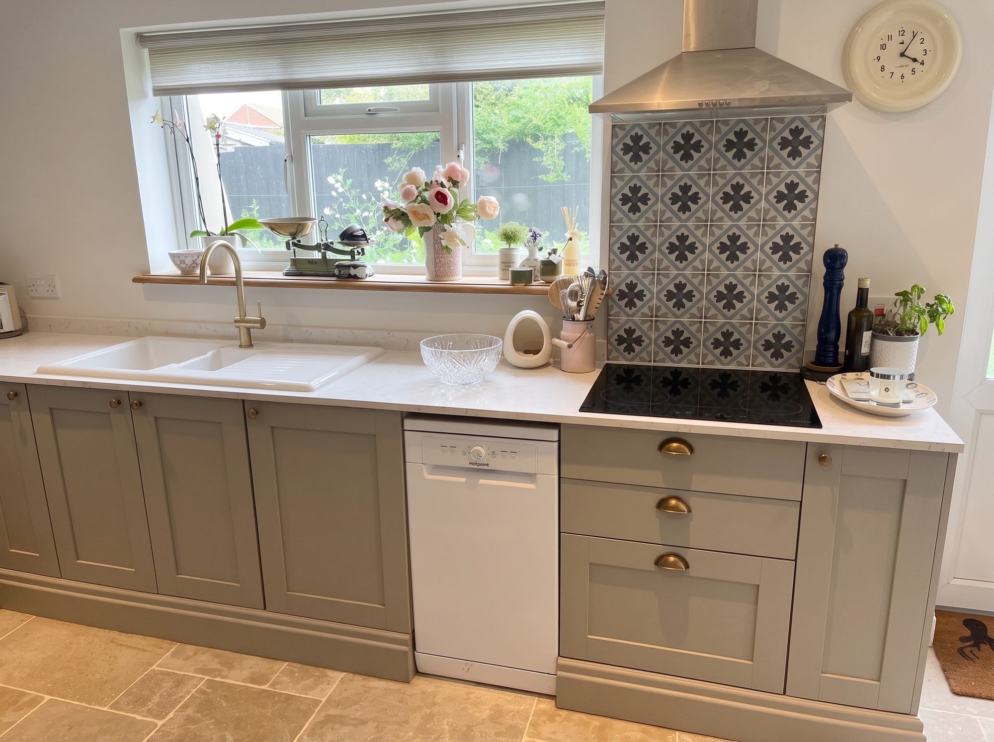 Shaker kitchen run with quartz worktop, patterned splashback and brass cup handles